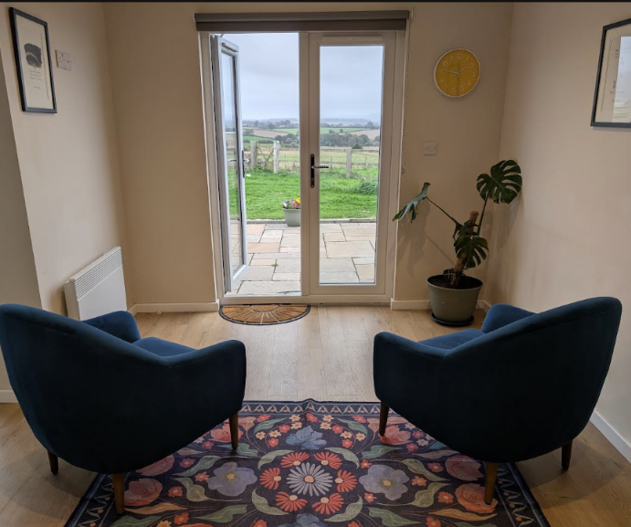 The counselling room, with two chairs facing French doors onto the countryside